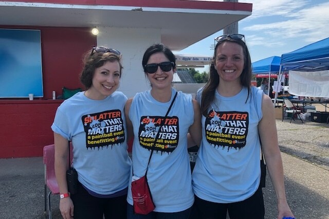 3 smiling adults wear shirts that promote splatter that matters