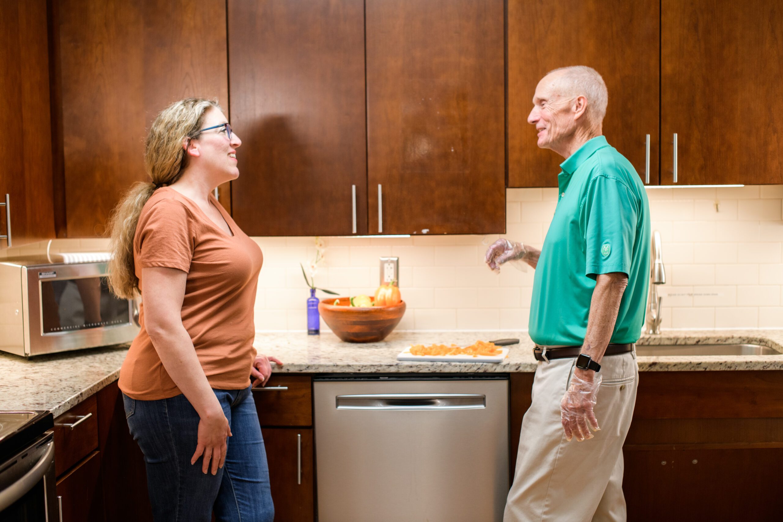 Two smiling adults chat in a kitchen