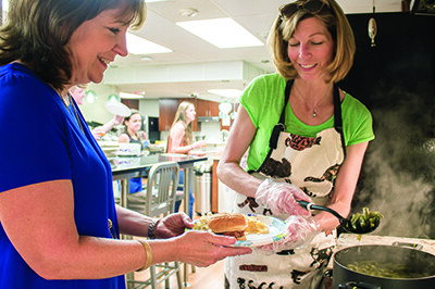 two smiling adults prepare a meal in a kitchen