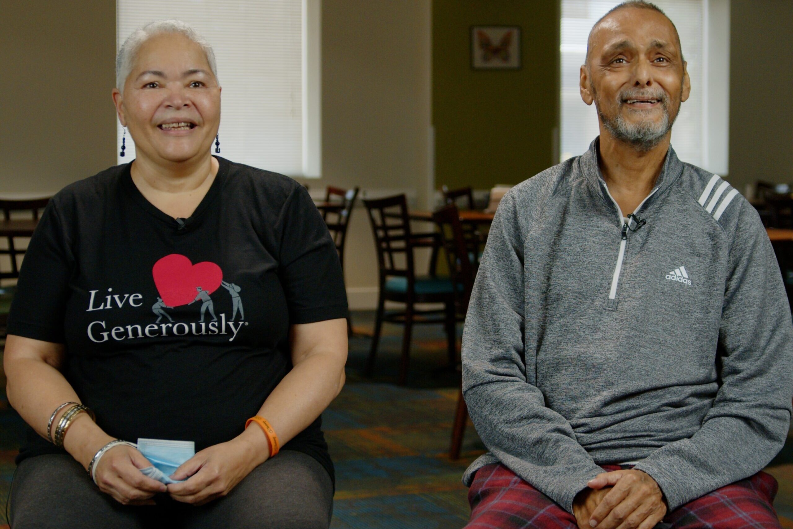 Two smiling adults sit in a dining room