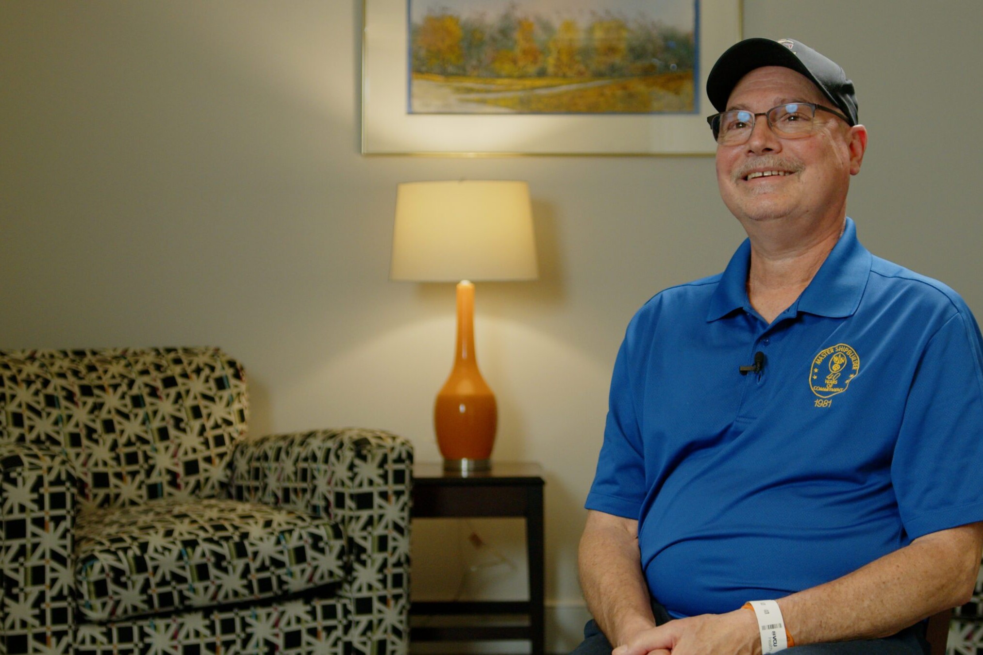 A smiling adult sits in a sitting room