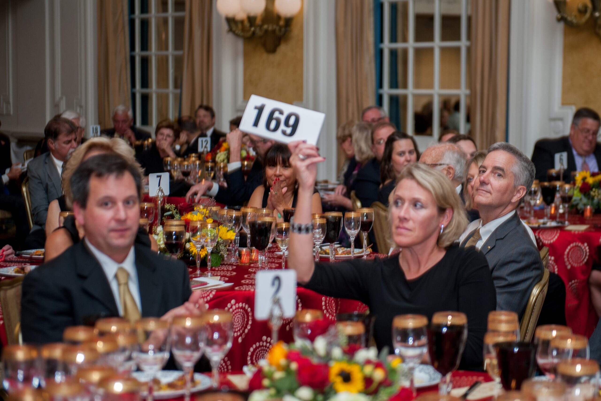 Focused adults hold up bid numbers at a live auction