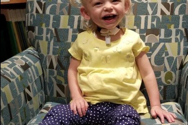 a young child laughs while sitting in a library chair at The Doorways