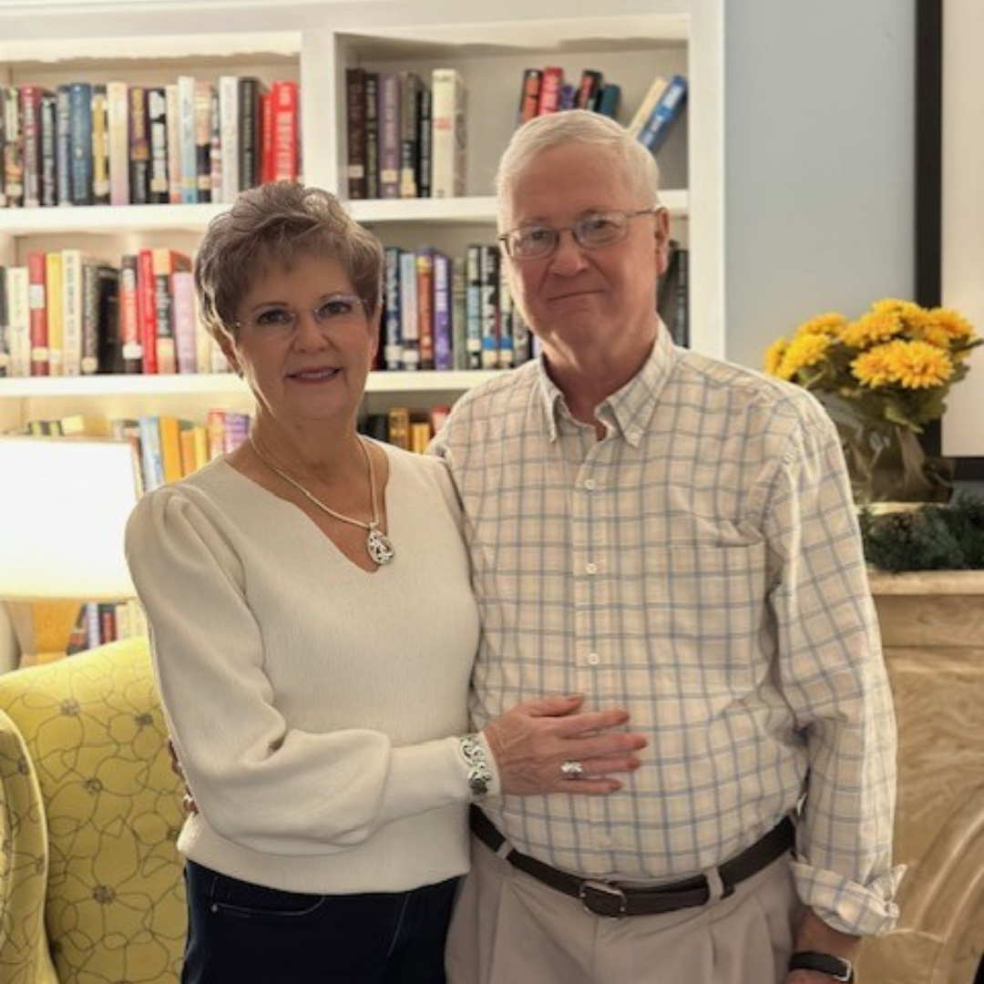 Two adults hug while standing inside a library