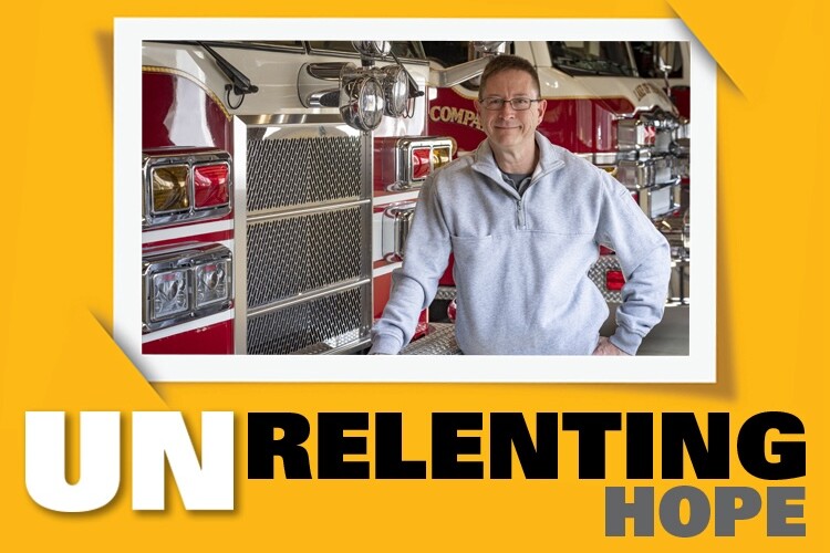 Photo of a smiling adult leaning against a firetruck with the words 