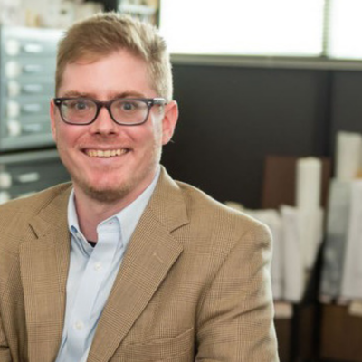 YPC member Alec Ball smiles in a suit in an office