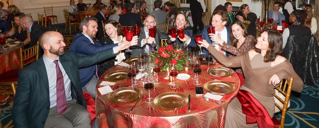 several adults toast with red glasses