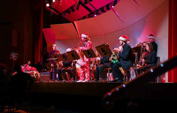 A group of musicians performs on a stage with festive outfits on