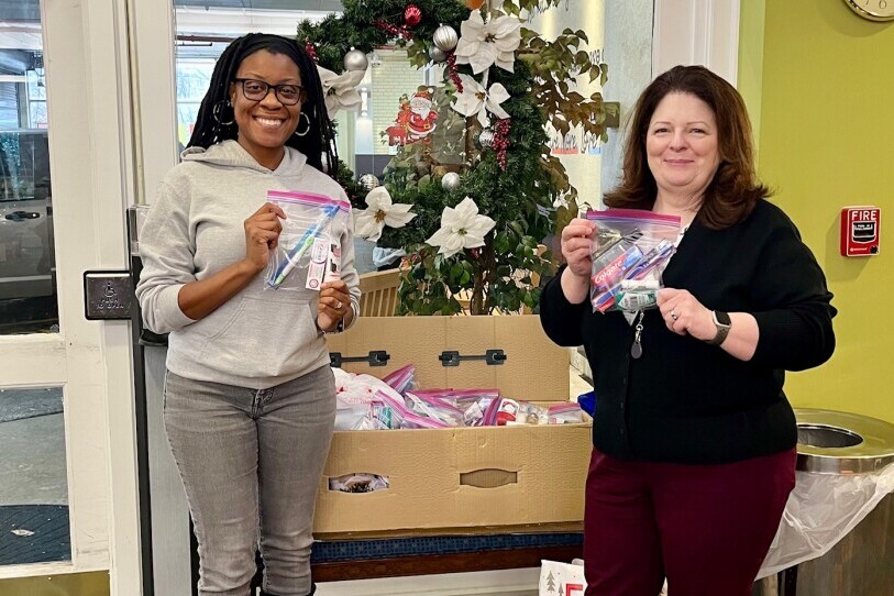 Two smiling VPM Employees at The Doorways holding toiletry bags