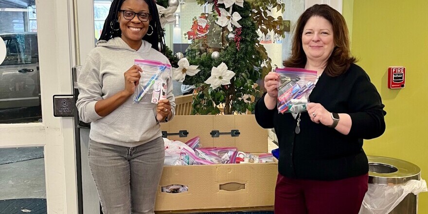 Two smiling VPM Employees at The Doorways holding toiletry bags