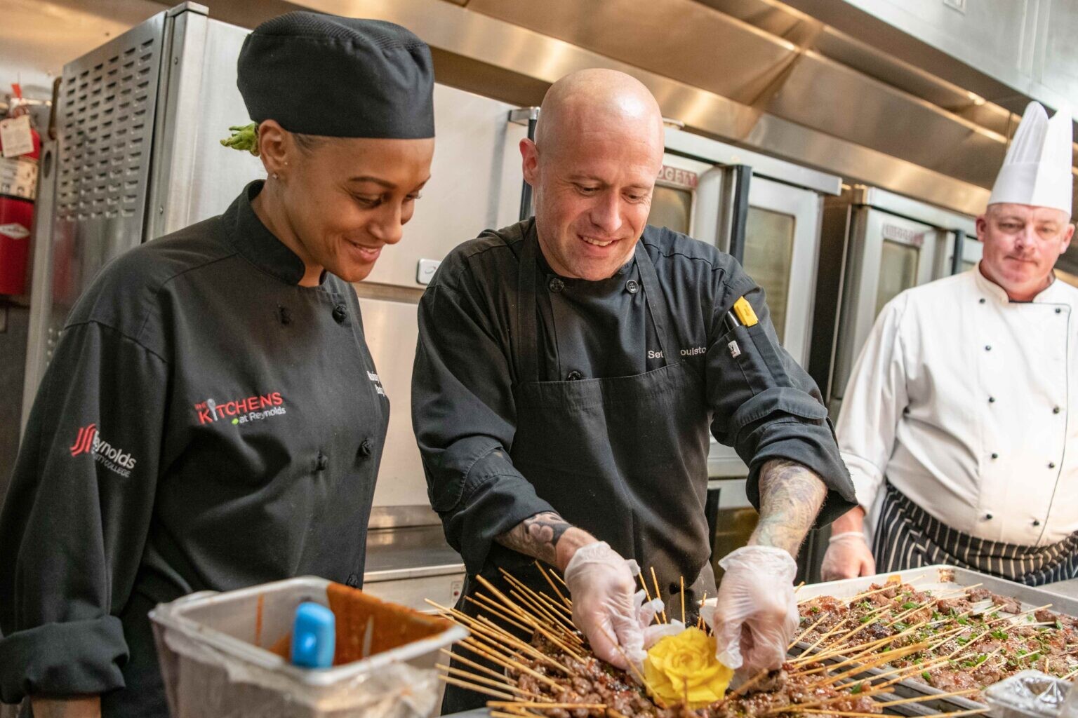 Three smiling chefs work on food