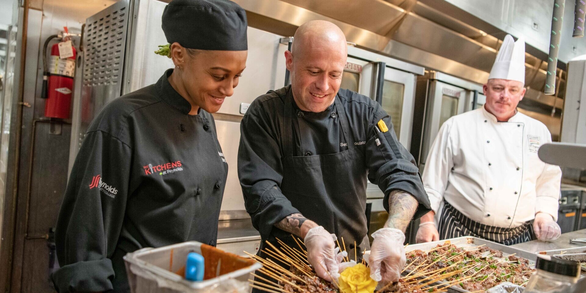 Three smiling chefs work on food