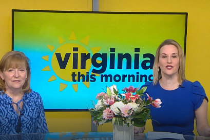 Two smiling people in a news studio with 