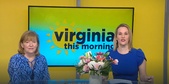 Two smiling people in a news studio with 