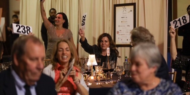 smiling adults hold up paddles during a live auction